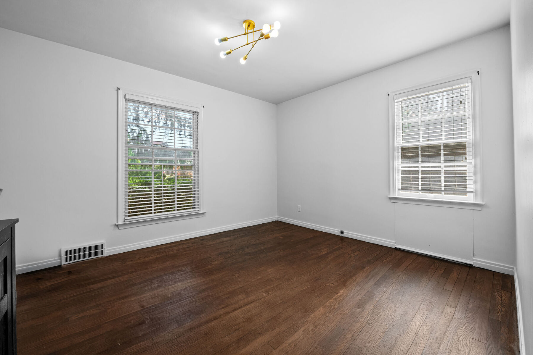 Bright main-level bedroom with hardwood floors and two windows at 3963 Yorkshire
